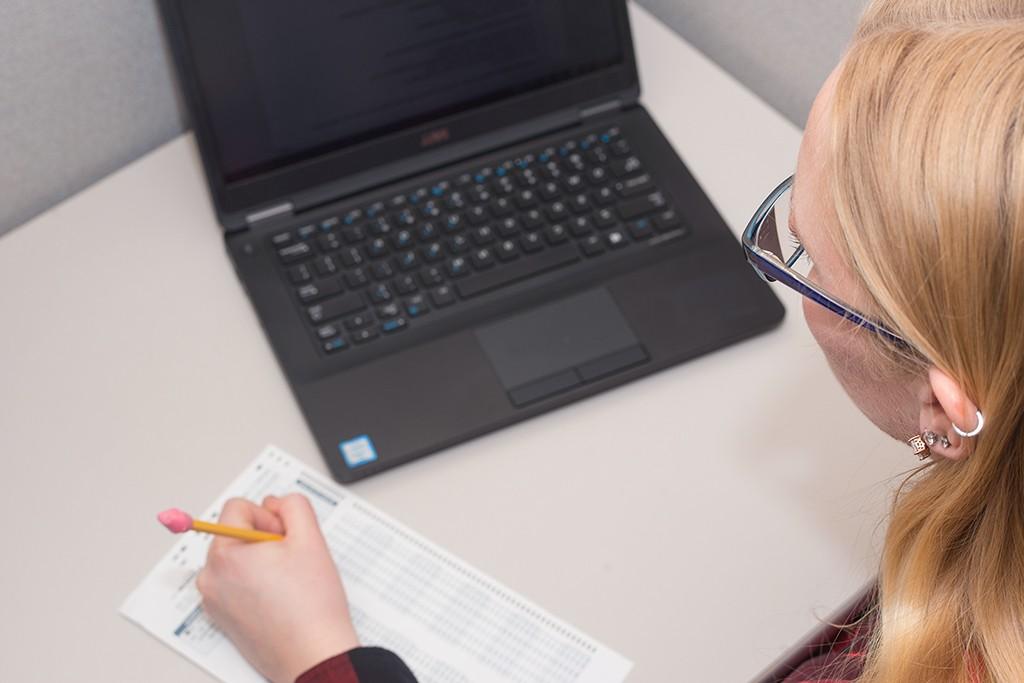 A student looks at a laptop as they fill out a multiple-choice test